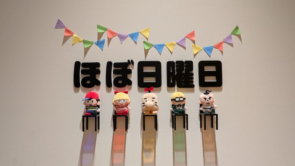 壁に飾られたゲーム”Mother2”のキャラクターのぬいぐるみと「ほぼ日曜日」という文字