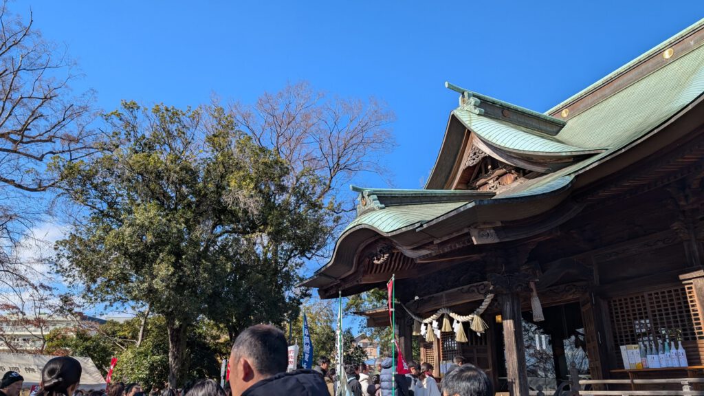 神社、初詣に並ぶ人の後ろ姿と青い空